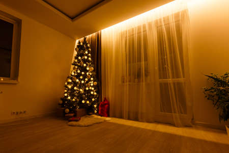 Illuminated Christmas tree decorated in modern living roomの写真素材