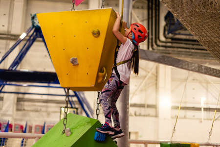 Little girl ascending in rock climbing gymの写真素材