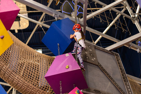 Girl wearing in harness and safety equipment climbing on practical wall indoor. Girl inserting the rope in a quickdraw.の写真素材