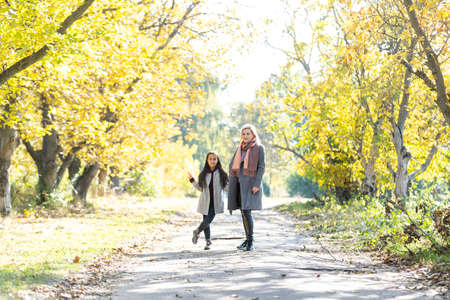 mother with her daughter in autumnal alleyの写真素材