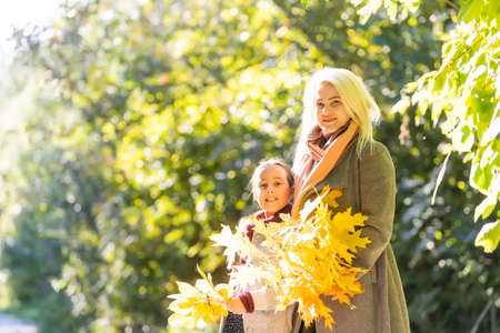 Fashionable mother with daughter. Family in a autumn park. Little daughter in a coat.の写真素材