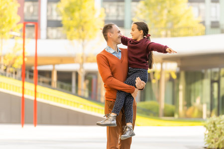 Adorable little girl with happy father walking in autumn park on a sunny dayの写真素材
