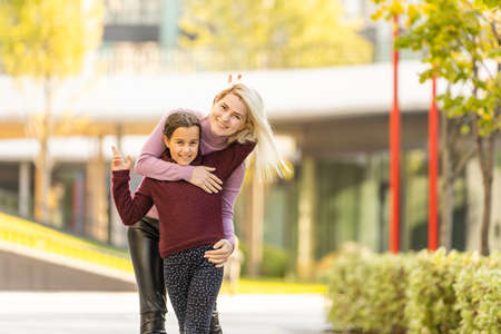 Young mother playing with her daughter in autumn parkの写真素材
