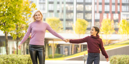 Little girl and her mother enjoy sunny weather in the autumn parkの写真素材