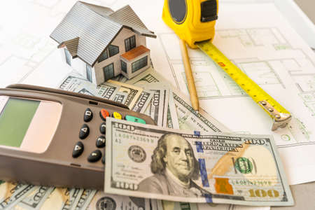 Money against the background of the house layout. Salary for builders. Vacancies for builders. Training in construction professions.の写真素材