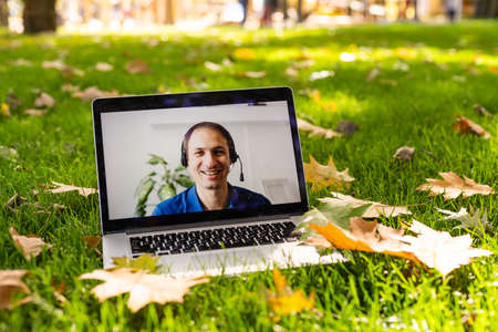 Image of autumn park and videocall by laptop computerの写真素材
