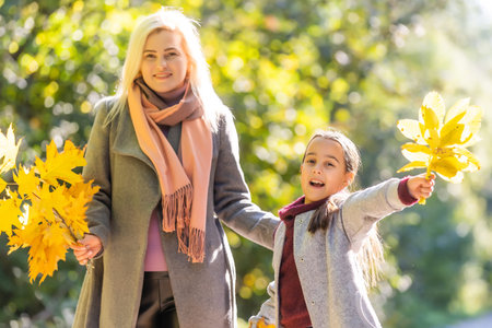 happy family: mother and child little daughter play on autumn walk in nature outdoors