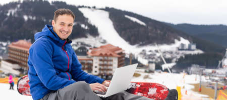 snowboarder typing on the laptop in the mountains winterの写真素材