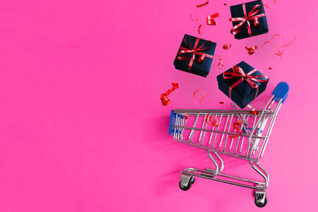 Christmas gifts and shopping in trolley isolated on pink background.の写真素材