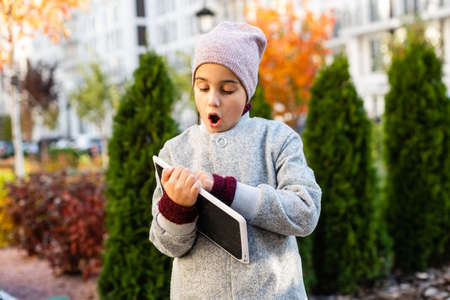 Happy little girl holding tablet PC outdoorsの写真素材