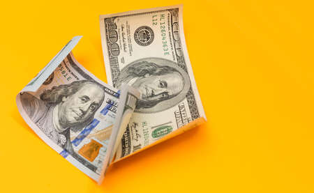 Single Hundred Dollar Bill Curled on yellowの写真素材