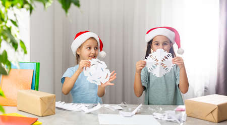girls holding snowflakes from the paper at home indoor. The holiday, childhood, winter, celebration conceptの写真素材