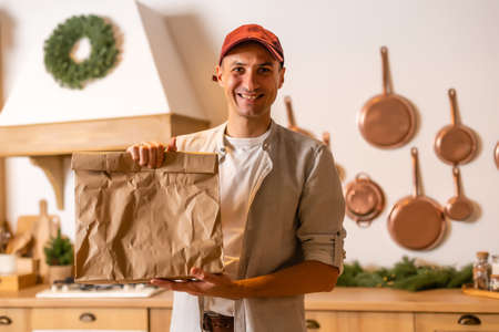 a delivery man with a package of food stands in a Christmas interiorの写真素材