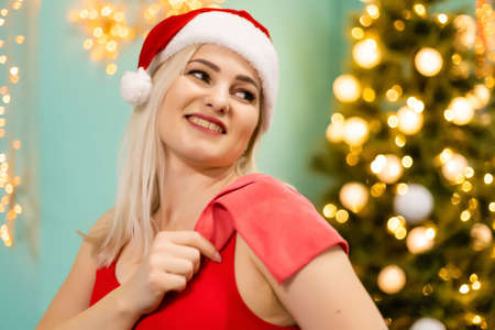 Christmas fitness woman smiling joyful and happy. Beautiful cheerful Caucasian female fitness model near christmas tree at the gymの写真素材