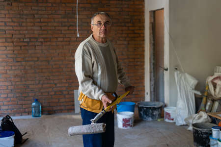 House Painting and Renovation Business Concept. Caucasian Male Painting House Room From the Ladder.の写真素材