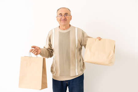 Portrait of pensioner elderly retired cheerful grey-haired man buying goods isolated over bright backgroundの写真素材