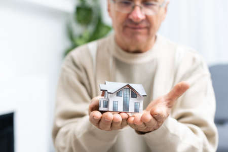 Portrait of handsome astonished person arm hold key small houseの写真素材