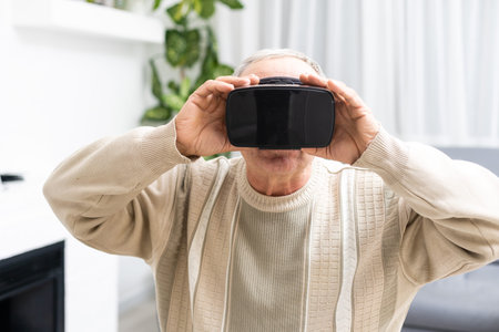 technology, augmented reality, gaming, entertainment and people concept - senior man with virtual headset or 3d glasses playing videogame at home.の写真素材