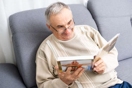 Grandfather looking at photo at homeの写真素材