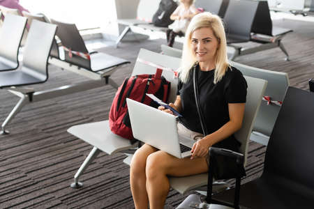 Business woman with suitcase in hall of airportの写真素材