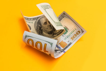 Single Hundred Dollar Bill Curled on yellow