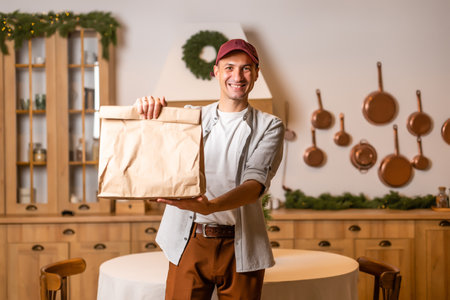 Young delivery man holding and carrying a cardbox. Buy food online in quarantine concept.の写真素材