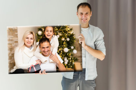 a man holding a photo canvas with a picture of christmasの写真素材