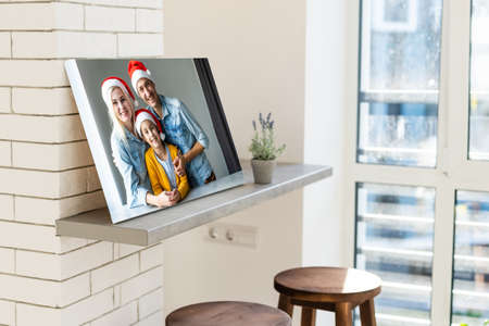 Photo printed on canvas, white background. Happy young family in Santa hats celebrating Christmas at homeの写真素材