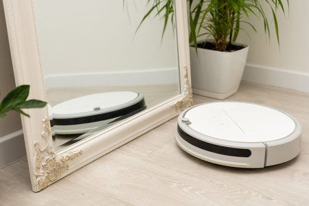 Robot vacuum cleaner cleaning laminate floor in room, nobody