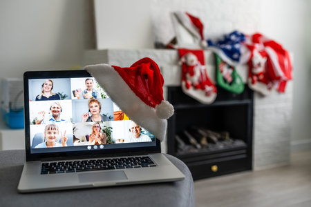 A young smiling woman wearing red Santa Claus hat making video call on social network with family...