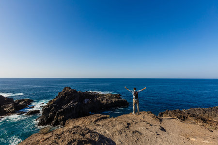 young bright attractive man standing on the ocean and controlling the situation on the beach. Ocean...