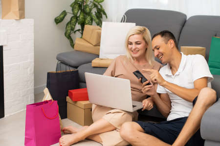 Laughing couple browsing the internet at the laptopの写真素材