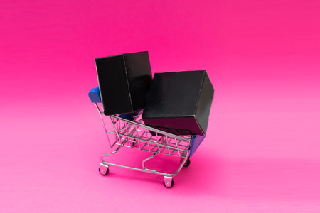 Shopping cart and giftboxes on pink background