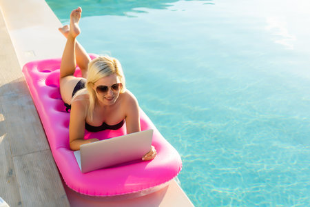 Sexy woman sunbathing and working on a chaise lounge near pool outdoorsの写真素材