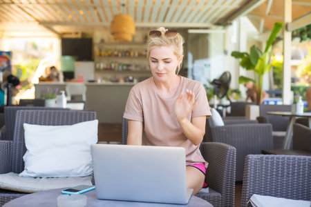 A side view photo of woman using laptop for e-shopping while sitting in a modern hotel lobby. A...