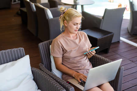 Young woman sitting on sofa at hotel lobby working laptop computerの写真素材