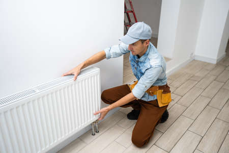 A man changes the heating in the house, radiators. The concept of modern heating, replacement of the old with a new one. Warmth in the houseの写真素材