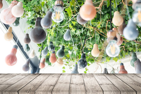 Wood table top on blurred of counter cafe shop with light bulb. Background for montage product...