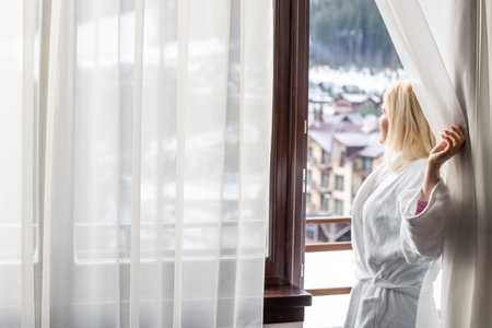woman in bathrobe on winter terrace in mountainsの写真素材