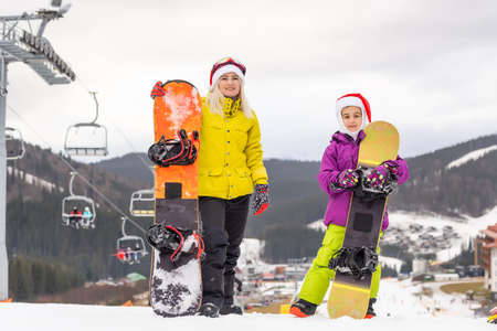 Portrait of happy family in Santa caps and snowboard at winter resortの写真素材