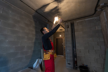 handsome young man electrician working on switchboard of house building construction site