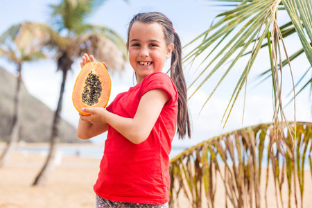 After playing on the sea black sand beach little cute girl picnics of natural vegetarian food -...