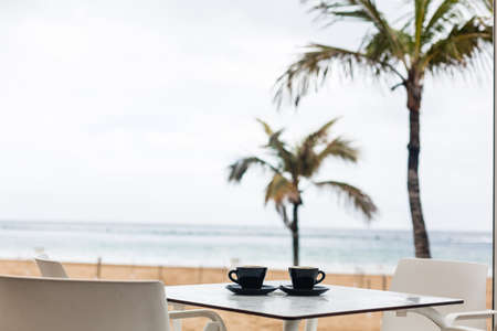 a cup of coffee on the beach and palm treeの写真素材