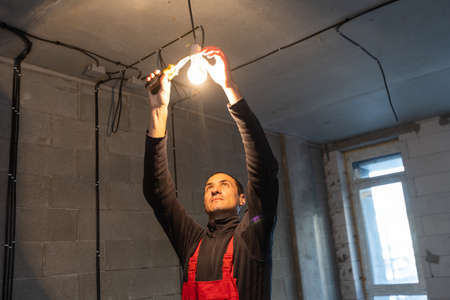 handsome young man electrician working on switchboard of house building construction siteの写真素材