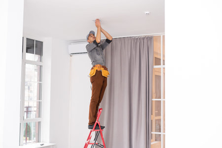 An electrician is installing spotlights on the ceiling
