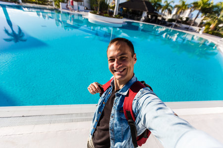 man takes a selfie near the pool