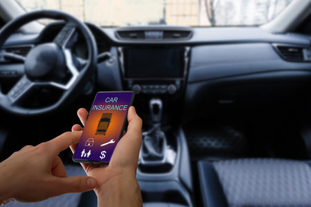 Handsome man hand holding smartphone to use car insurance application online after his broken car....