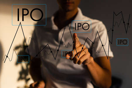 IPO - Initial Public Offering concept with hand pressing a button on blurred abstract background.の写真素材
