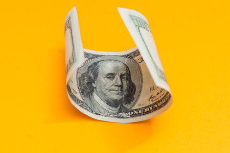 Single Hundred Dollar Bill Curled on yellowの写真素材