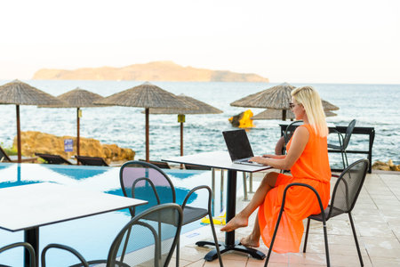 Woman using laptop computer by the swimming pool